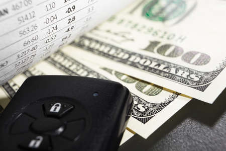 Stock data showing negative result over one hunder dollar bills and car alarm deviceの写真素材