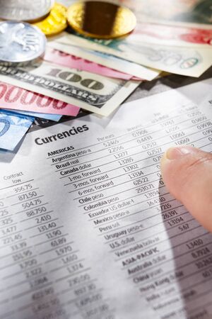 Hand observing the foreign exchange data with money from different countries on edgeの写真素材