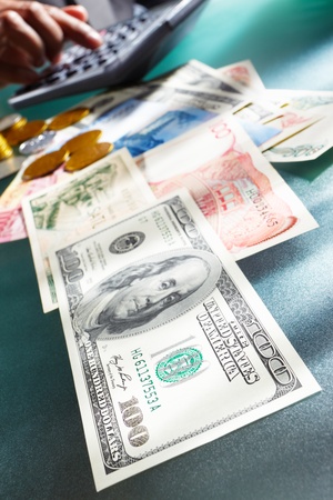 Us dollar bill with several foreign money on the table with people hand doing accounting on backgroundの写真素材
