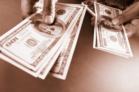 Busineswoman hand counting US dollar bills, taken close up, in sepia color