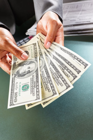 Busineswoman hand counting US dollar bills, taken close up