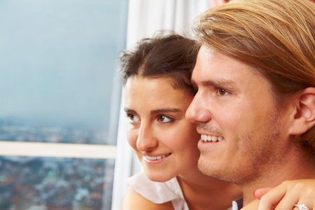 Happy couple looking away to the window with blue sky as background. ***の写真素材