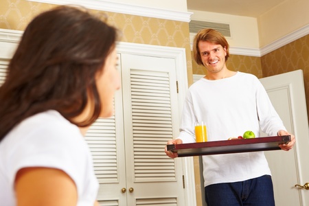 Man delivering breakfast on the tray to her spouse on bed in the morningの写真素材