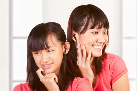 Two Chinese girls listening to the music through earphoneの写真素材