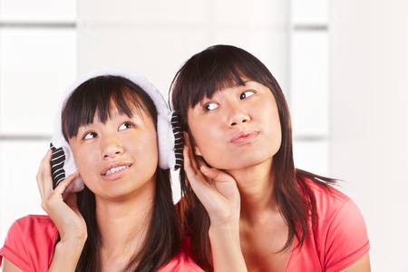 Two Chinese girls listening to the music through headphoneの写真素材