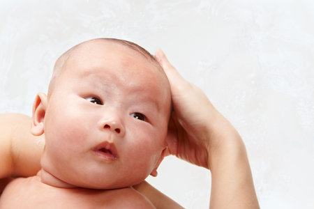 Baby's head being shampooed, with water as background