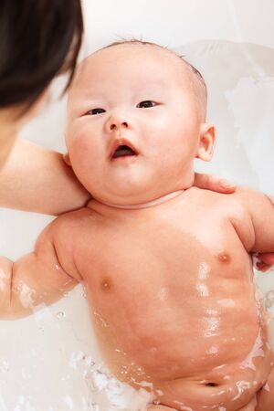 Chinese baby boy being bathed by his mom.の写真素材