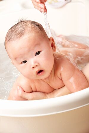 Chinese baby boy being bathed by his mom.の写真素材