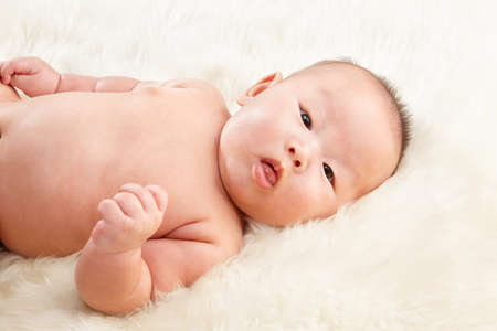 Chinese baby boy face taken close up lying on fur bedの写真素材