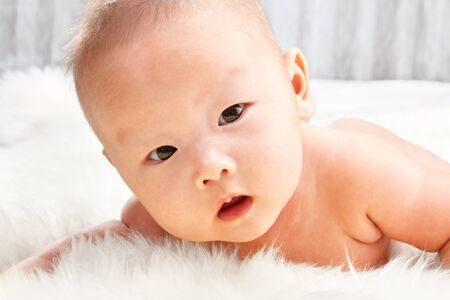 Chinese baby boy face taken close up lying on fur bedの写真素材