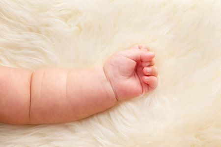 Hand of Chinese baby lying on fur bed