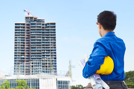 Male contractor or civil engineer looking at the bulding project on progress