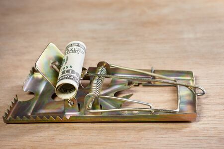 Mousetrap placed on with money as the bait, on wooden floorの写真素材