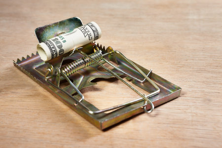 Mousetrap placed on with money as the bait, on wooden floorの写真素材