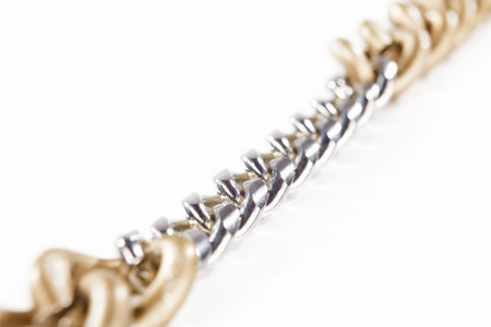 Golden chain connected with small siver chains, isolated against white background. small depth of...