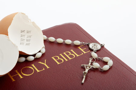 Roman number forty marked inside an empty egg shell, with rosary necklace put on the bible
