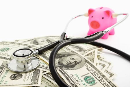 Pink piggy bank using stethoscope checking the dollar billsの写真素材