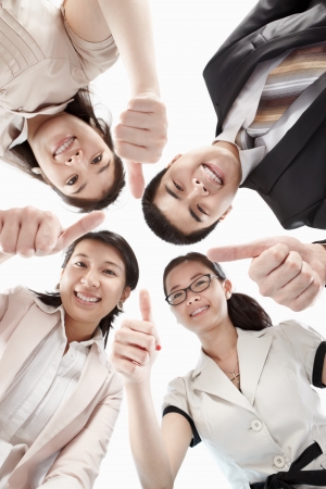 Four business people looking to camera from low angle with thumb upの写真素材