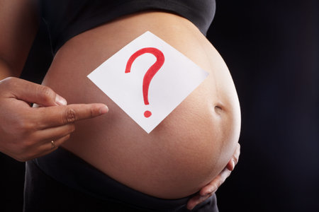 Pregnant lady's stomach and qustion mark for unknow fetus gender over black background