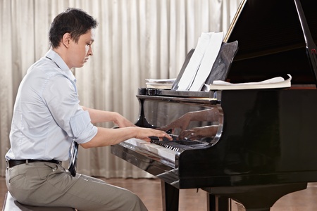 A young man playing piano on the stageの写真素材
