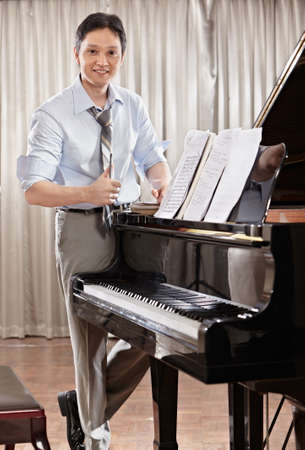 A young music composer standing near grand pianoの写真素材