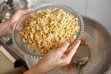 Hand holding a plate with fried rice which has been finishedの写真素材