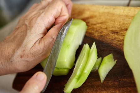 Hand cutting chayote as ingredient for cookingの写真素材