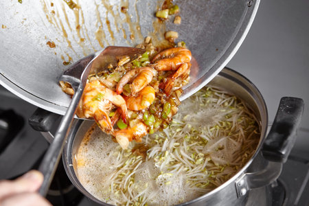 Adding the stir fried shrimp with leek and garlic to the soup