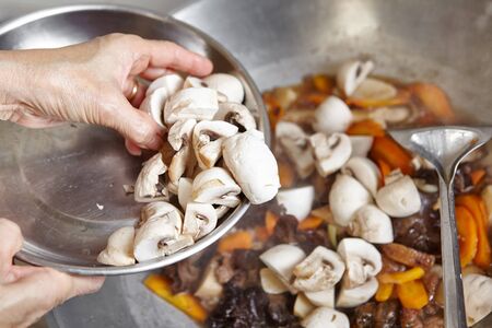 Adding mushroom to the cooking on the wokの写真素材