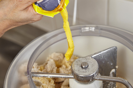 Adding ingredient to batter machine to make bread doughの写真素材
