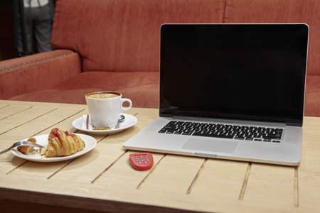 Laptop; e banking token; croissant and coffe on cafe's tableの写真素材