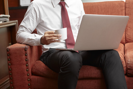 unrecognizable businessman using laptop while enjoying coffee in cafeの写真素材