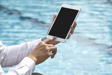 unrecognizable businessman using phone on pool sideの写真素材