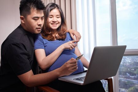Asian young couple buying online to prepare for the babyの写真素材