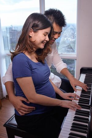 Asian young couple playing piano fot the baby in the wombの写真素材