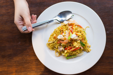 Stir-fried noodles , Chow mein , Chinese cuisine on wooden background and women  handの写真素材