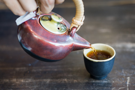 pouring tea into cup of tea with man handの写真素材