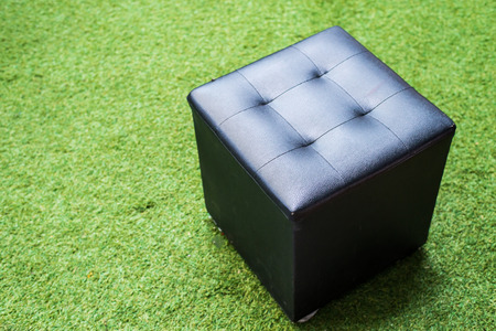 Black chair on green grass texture , cube chairの写真素材