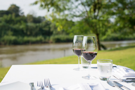 red wine on table set and  green grass background in the gardenの写真素材