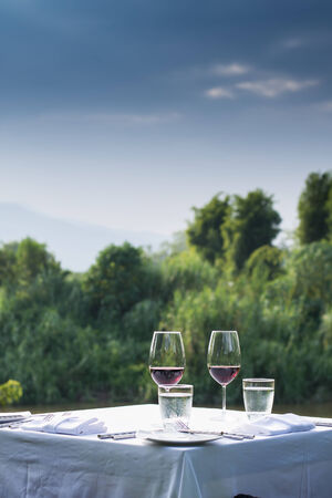 red wine on table set and  green grass background in the gardenの写真素材