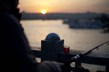 Man fishing from bridge in evening lightの写真素材