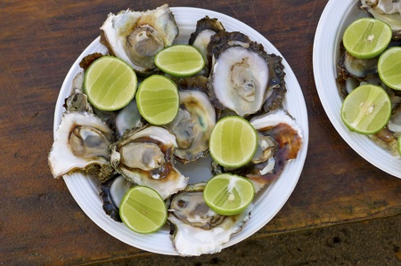 Plate of raw oysters with sliced limes, served in Puerto Vallarta, Mexicoの写真素材