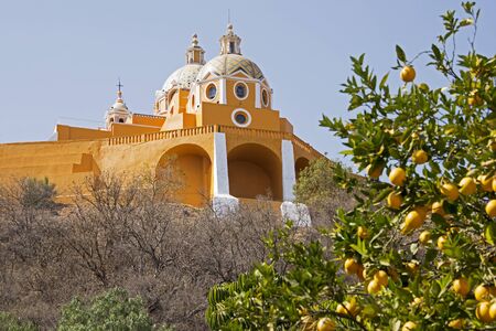Section of Our Lady of Los Remedios church in Cholula, Mexico with orange tree in foregroundの写真素材