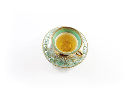 Top view of green and white teacup and saucer with tea, isolated on whiteの写真素材