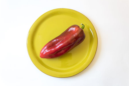 Ripe red Capsicum annuum Cubanelle pepper, Cuban pepper, Italian frying pepper, on bright green plate, food ingredient, isolated on white, horizontal aspectの写真素材