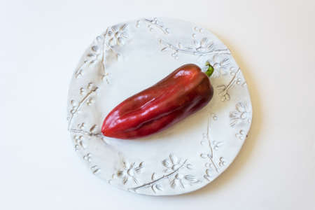 Big red ripe Capsicum annuum Cubanelle pepper, Cuban pepper, Italian frying pepper, on bright white plate, food ingredient, isolated on white, horizontal aspectの写真素材