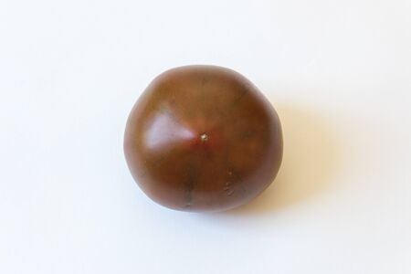 Blossom end view of a deep red green Cherokee Purple organic heirloom tomato food ingredient, isolated on white, horizontal aspectの写真素材