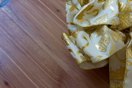 White and gold Christmas ribbon against a diagonal wood grain background, copy space, horizontal aspectの写真素材
