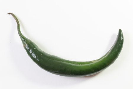Single curved chilaca pepper, ample copy space, isolated on white, horizontal aspectの写真素材