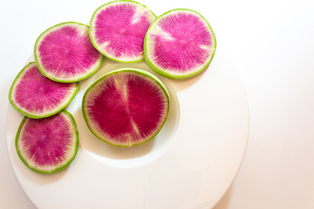 Fanned out slices of watermelon radish on a white plate, copy space, horizontal aspectの写真素材